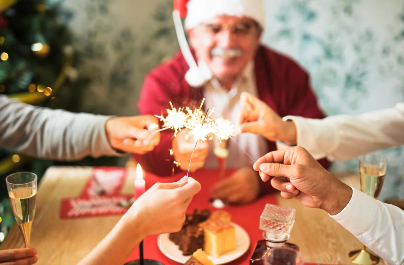 A family holds sparklers above the table for a holiday family dinner