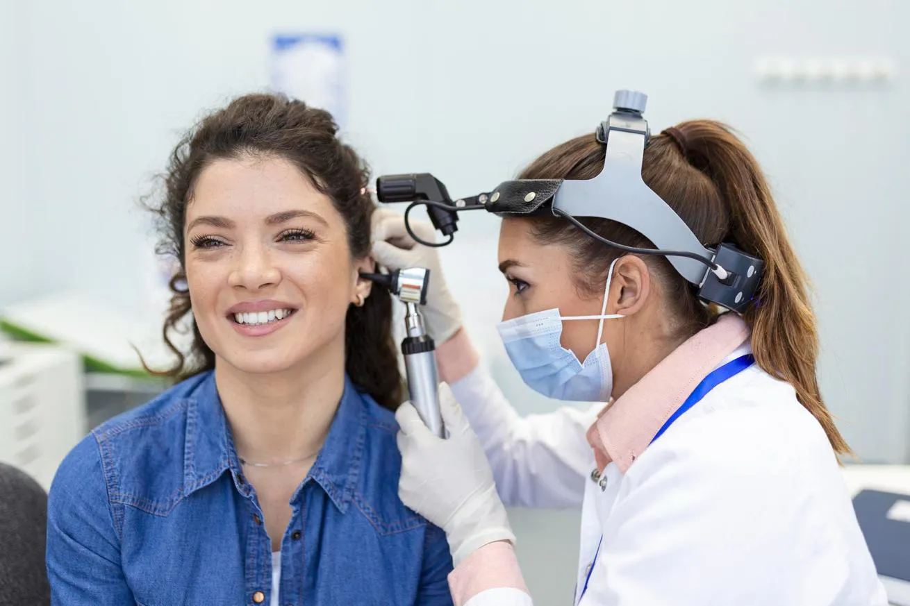 An audiologist applies an otoscope